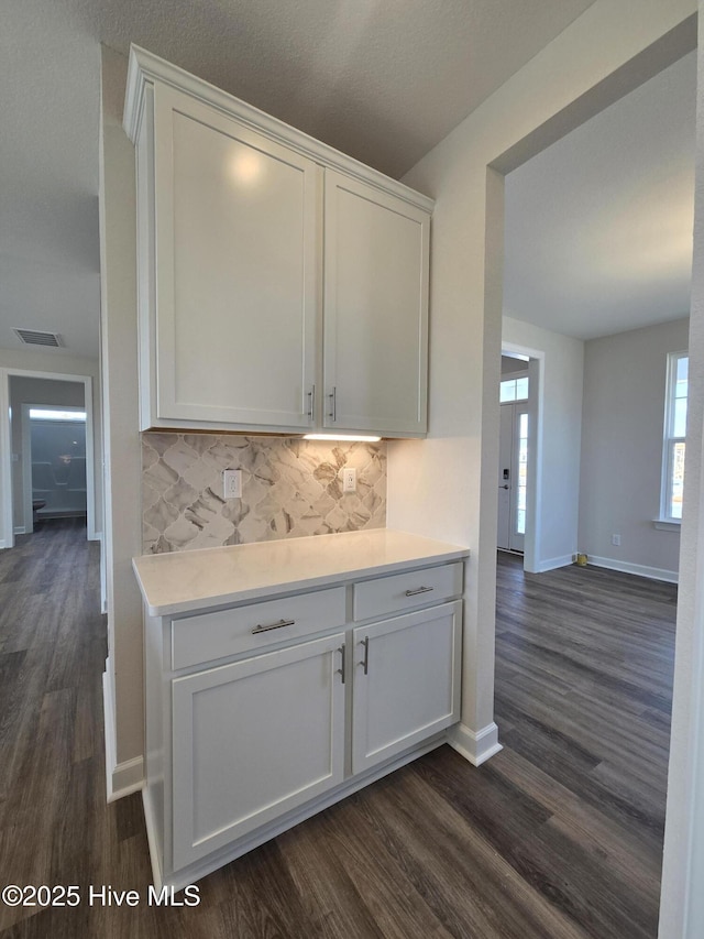 kitchen with tasteful backsplash, white cabinetry, and dark wood-type flooring