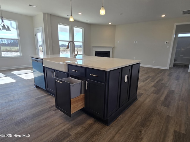 kitchen featuring an island with sink, pendant lighting, sink, and stainless steel dishwasher