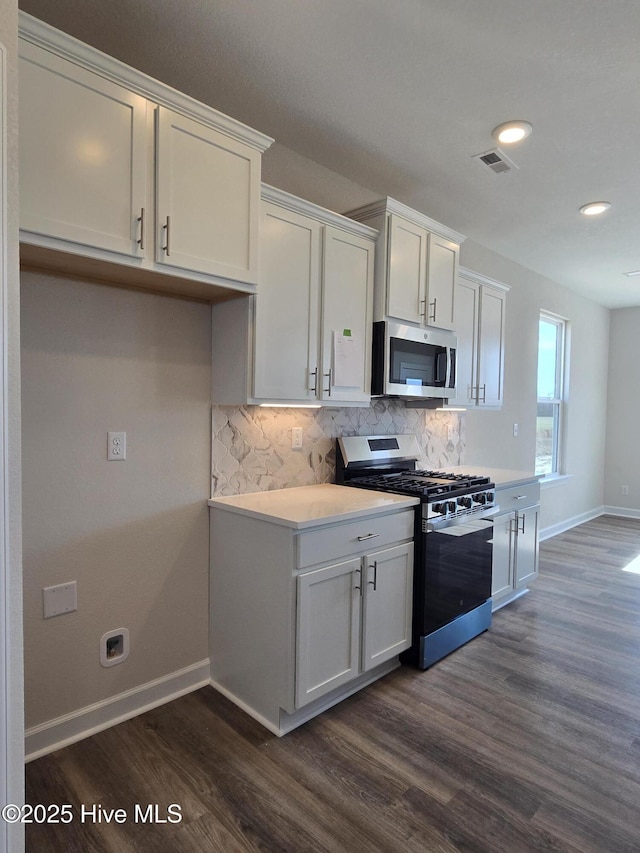 kitchen featuring white cabinetry, stainless steel appliances, dark hardwood / wood-style flooring, and tasteful backsplash