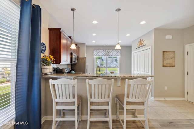 kitchen featuring light tile patterned floors, kitchen peninsula, appliances with stainless steel finishes, tasteful backsplash, and pendant lighting