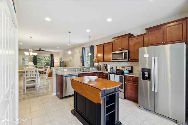 kitchen with appliances with stainless steel finishes, pendant lighting, kitchen peninsula, and a center island