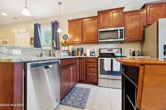 kitchen featuring light tile patterned floors, stainless steel appliances, tasteful backsplash, hanging light fixtures, and sink