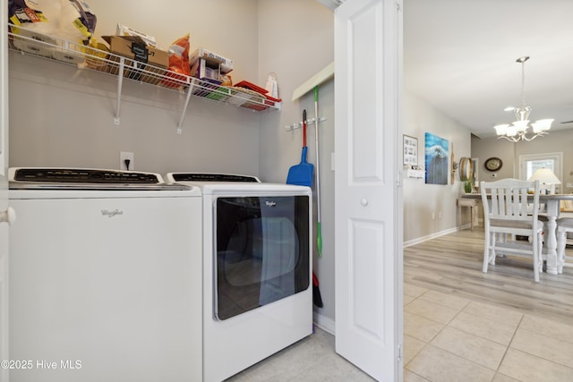 laundry area with light tile patterned flooring, washer and clothes dryer, and a notable chandelier