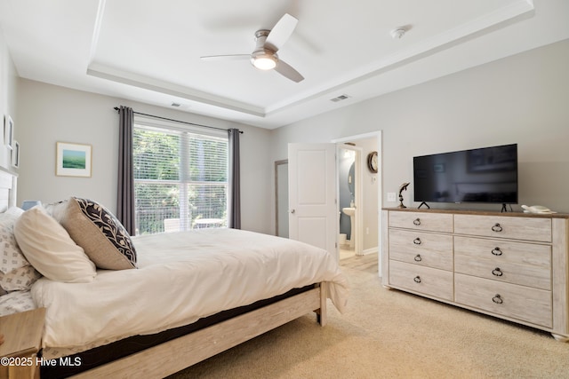 bedroom featuring light carpet, ceiling fan, and a tray ceiling