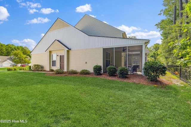 rear view of property featuring ceiling fan, a lawn, and a sunroom