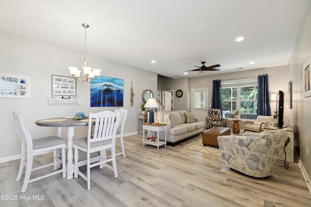 interior space with ceiling fan with notable chandelier and light wood-type flooring