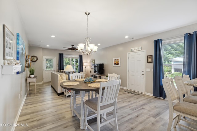 dining room with ceiling fan with notable chandelier and light hardwood / wood-style flooring