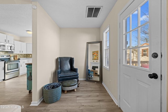 living area with a textured ceiling and light wood-type flooring