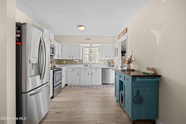 kitchen featuring blue cabinetry, appliances with stainless steel finishes, white cabinetry, and sink