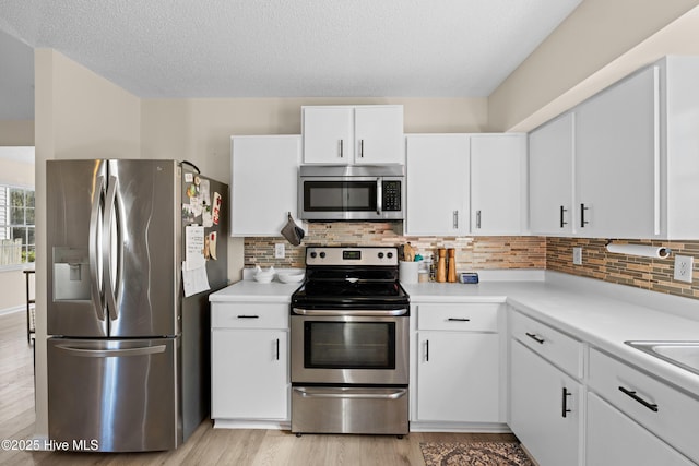 kitchen with appliances with stainless steel finishes, tasteful backsplash, and white cabinetry