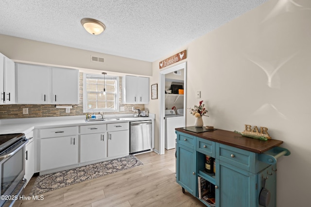 kitchen featuring stove, stainless steel dishwasher, blue cabinets, washer and clothes dryer, and white cabinets