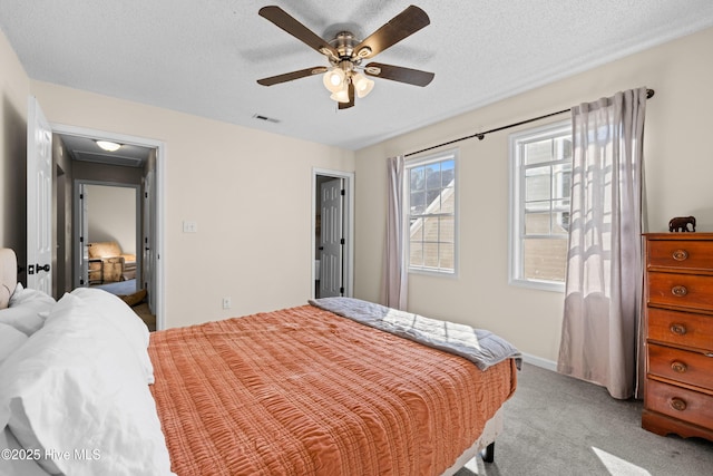 bedroom with ceiling fan, light colored carpet, and a textured ceiling