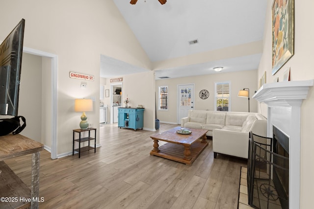 living room with light wood-type flooring, high vaulted ceiling, and ceiling fan