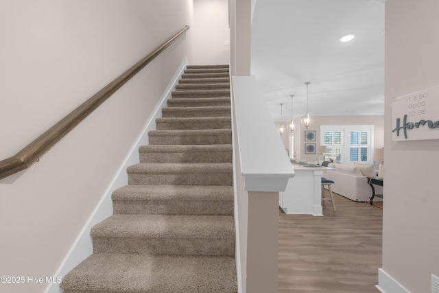 stairway featuring wood-type flooring and a notable chandelier