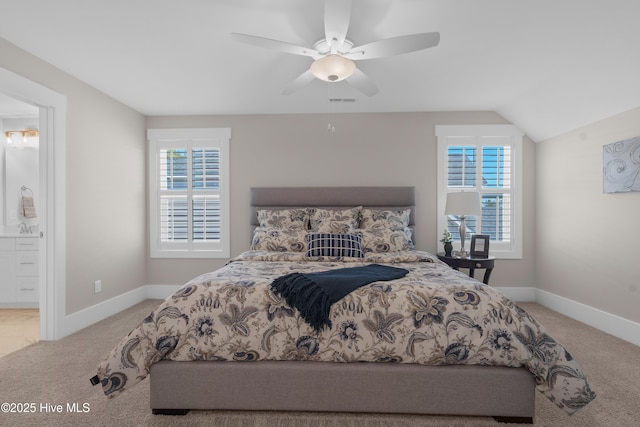 carpeted bedroom featuring ensuite bathroom, ceiling fan, multiple windows, and vaulted ceiling