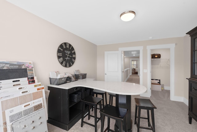 kitchen with a breakfast bar area, kitchen peninsula, and light colored carpet