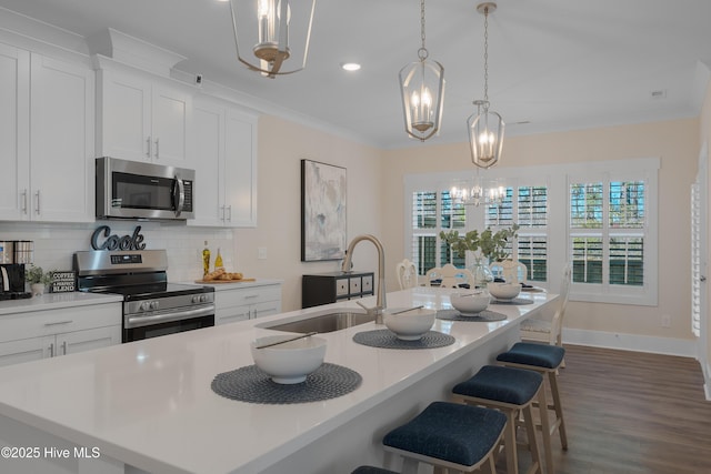 kitchen with pendant lighting, stainless steel appliances, and a kitchen island with sink