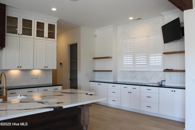 kitchen with white cabinetry, tasteful backsplash, ornamental molding, and dark stone counters