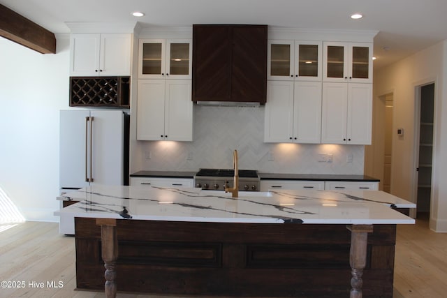 kitchen with light hardwood / wood-style flooring, high end refrigerator, backsplash, and a spacious island