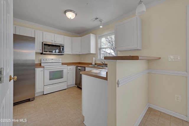 kitchen featuring kitchen peninsula, appliances with stainless steel finishes, ornamental molding, sink, and white cabinetry