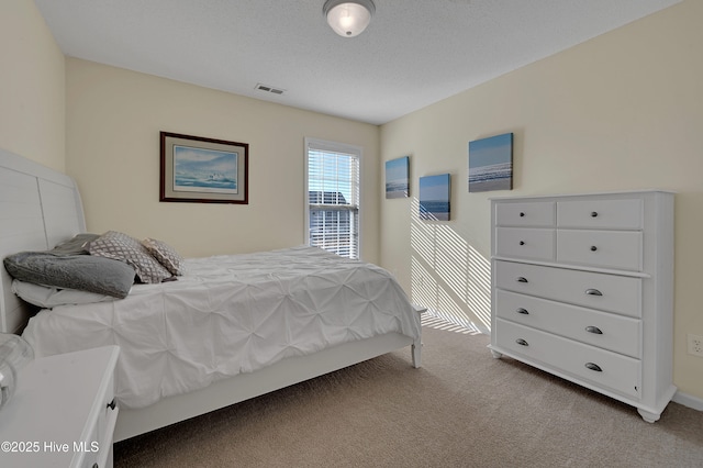 bedroom with light colored carpet and a textured ceiling