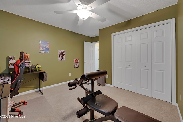 workout area featuring light carpet, a textured ceiling, and ceiling fan