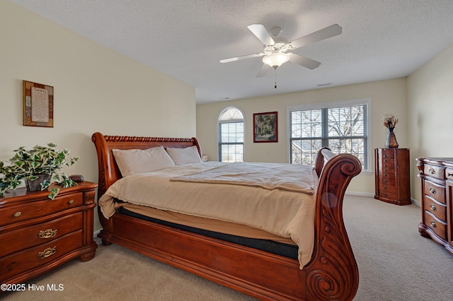 carpeted bedroom featuring ceiling fan and a textured ceiling