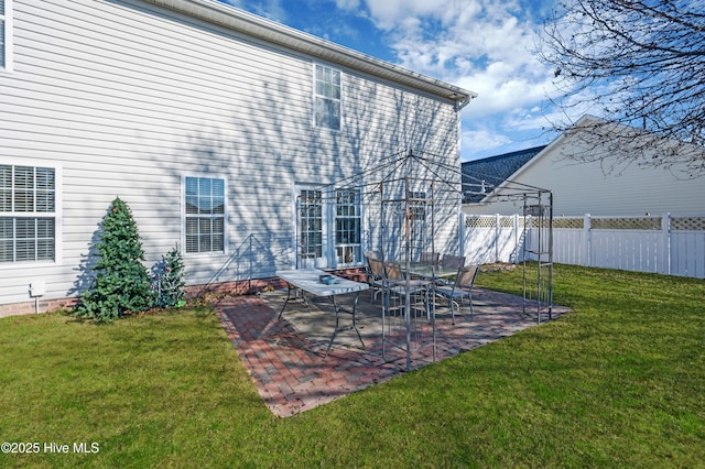 rear view of house featuring a lawn and a patio