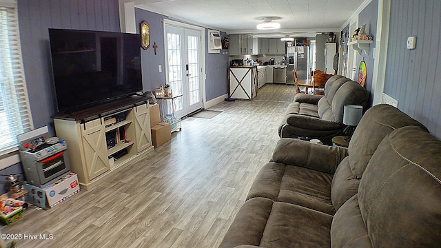 living room featuring french doors, light wood-type flooring, and crown molding