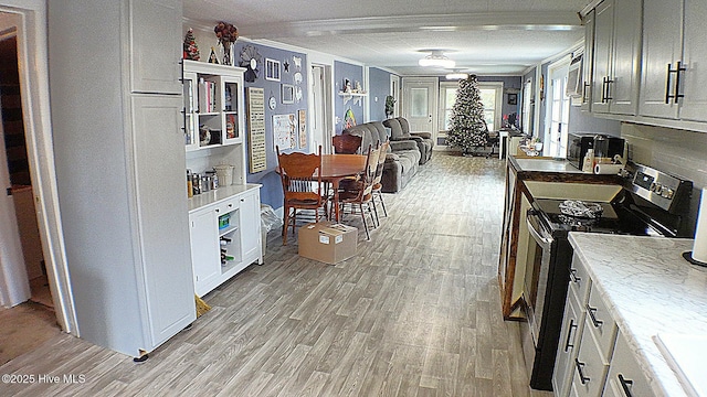 kitchen featuring light wood-type flooring, electric range, and white cabinetry