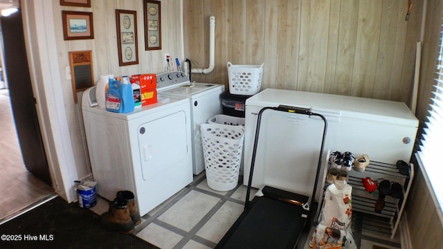 laundry area featuring wood walls, washing machine and dryer, and light tile patterned flooring