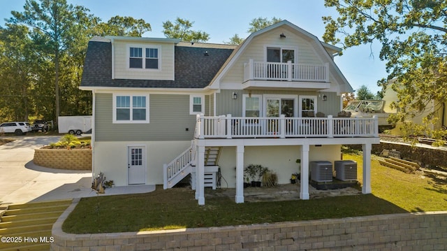 rear view of property with central AC unit, a balcony, a yard, and a deck