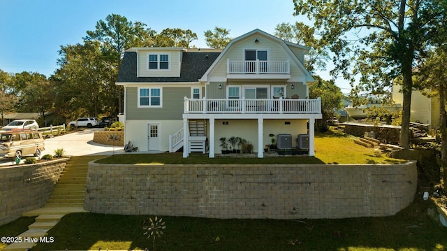 rear view of house with a balcony, a lawn, and central air condition unit