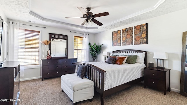 bedroom with ceiling fan, light colored carpet, crown molding, and a tray ceiling