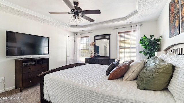 carpeted bedroom featuring ceiling fan, ornamental molding, and a raised ceiling