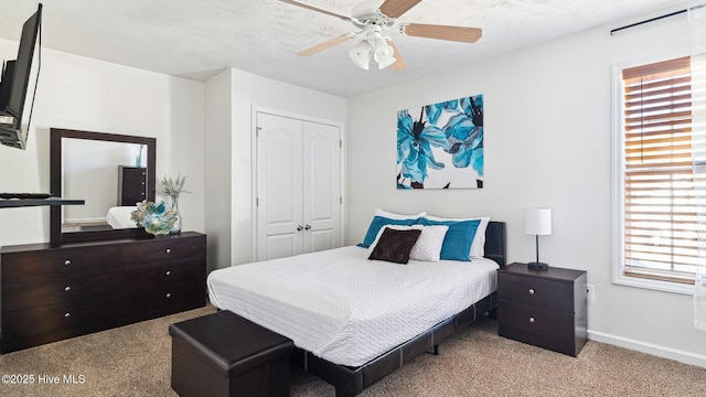 bedroom featuring ceiling fan, light colored carpet, a closet, and a textured ceiling