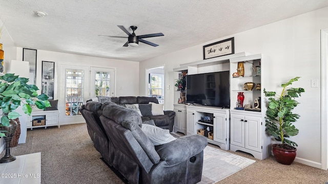 carpeted living room featuring ceiling fan and a textured ceiling