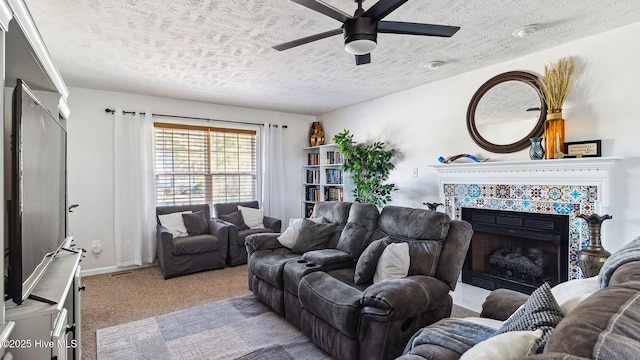 carpeted living room featuring ceiling fan, a textured ceiling, and a tile fireplace