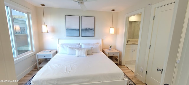 bedroom with ceiling fan, light hardwood / wood-style flooring, ensuite bathroom, and sink