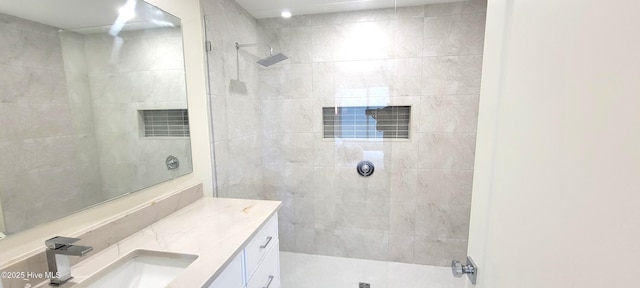 bathroom featuring tiled shower and vanity