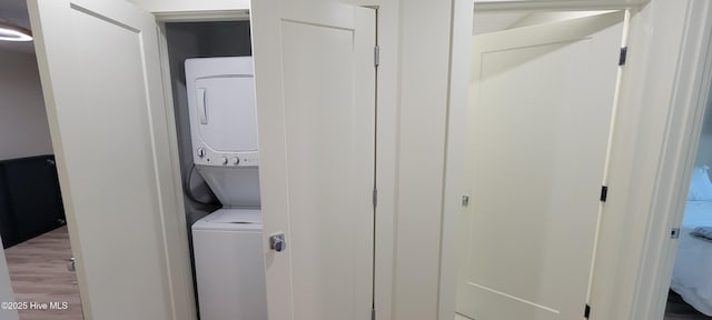 washroom with wood-type flooring and stacked washer / dryer