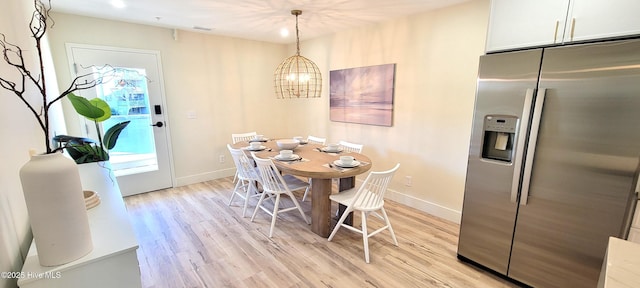 dining area with light hardwood / wood-style flooring and an inviting chandelier