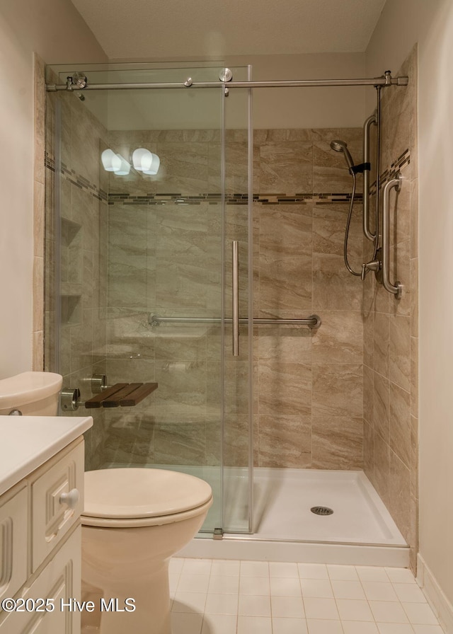 bathroom with a shower with shower door, tile patterned floors, vanity, and toilet