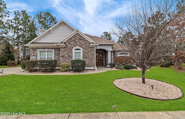 view of front facade featuring a front yard, brick siding, and roof with shingles