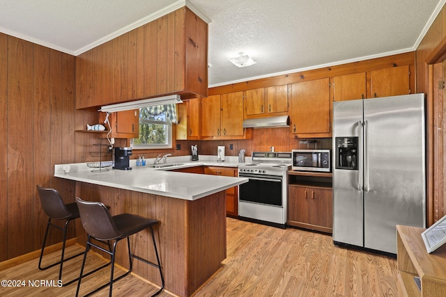 kitchen with sink, stainless steel appliances, light hardwood / wood-style flooring, kitchen peninsula, and ornamental molding