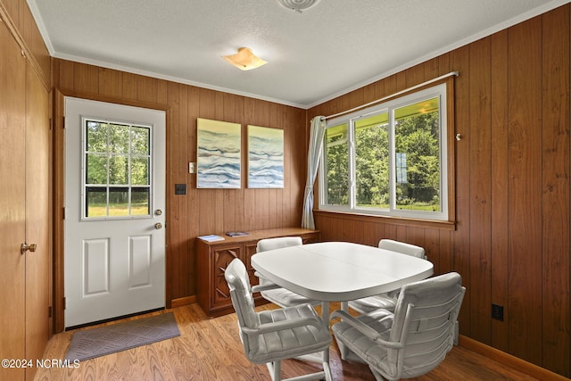 dining area featuring a textured ceiling, a healthy amount of sunlight, light hardwood / wood-style floors, and crown molding