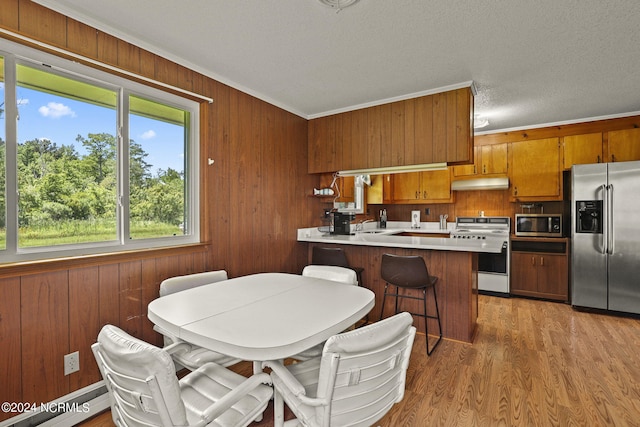 interior space featuring kitchen peninsula, ornamental molding, stainless steel appliances, and a breakfast bar area