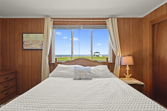 bedroom with a textured ceiling, crown molding, and wood walls