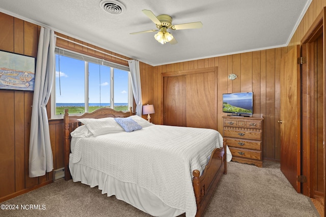 carpeted bedroom featuring crown molding, ceiling fan, and wooden walls