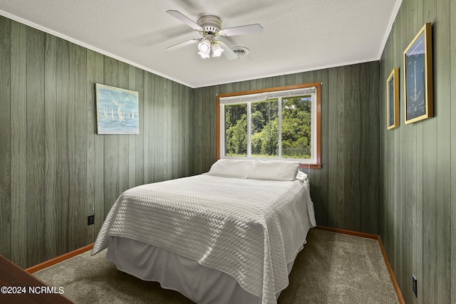 carpeted bedroom featuring ceiling fan, wood walls, ornamental molding, and a textured ceiling